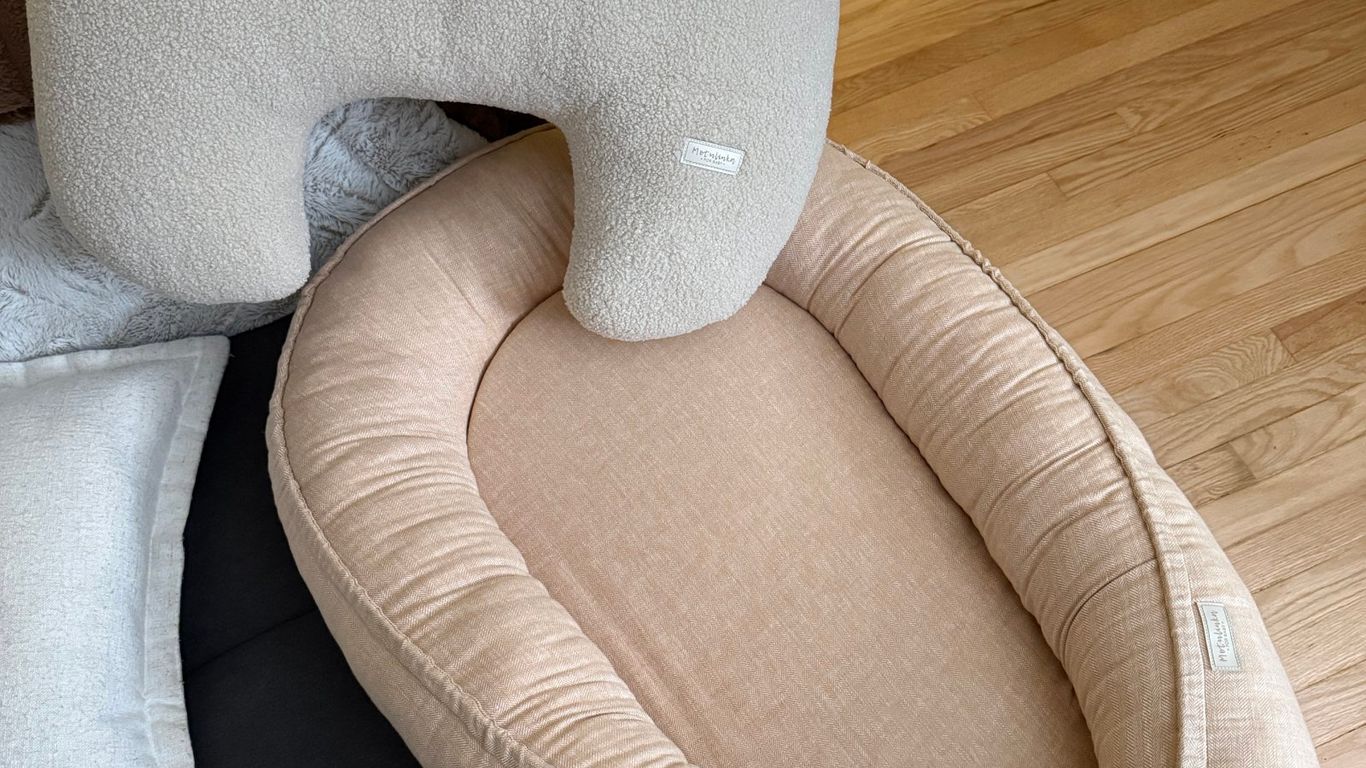 A baby nest and pillow with a bow on a wooden floor.