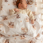 Baby lying on a crib with teddy bear patterned bedding