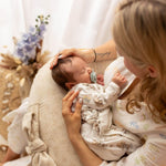 Woman holding a baby on a cushion with a soft, blurred background