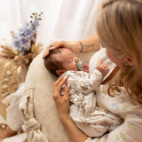 Woman holding a baby on a cushion with a soft, blurred background